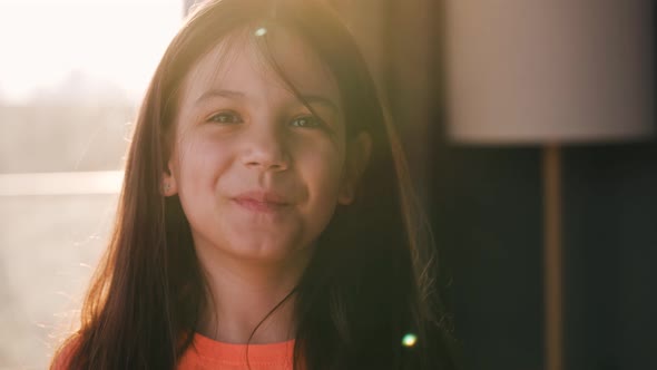 Portrait of a Brunette Girl Looking at the Camera and Smiling at Sunset