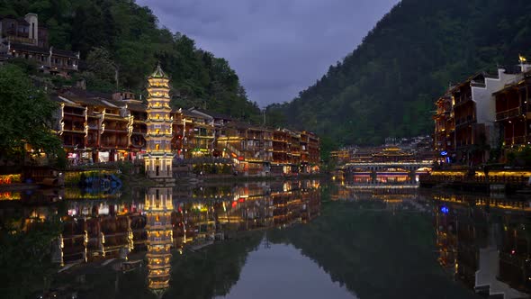 Traditional Chinese Tower and Houses on Both Banks of the River with Night Illumination During Dusk