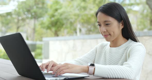 Woman typing on notebook computer at outdoor