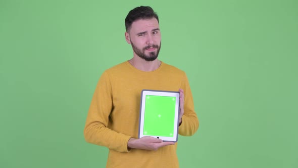 Stressed Young Bearded Man Showing Digital Tablet