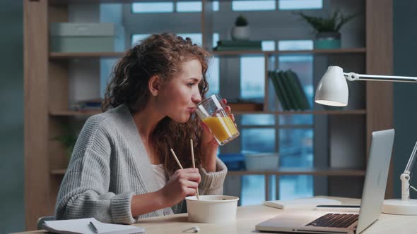 Attractive Woman Looking on Laptop and Eating in Evening Home