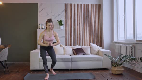 Young fit woman wearing sportswear do power exercise indoors in living room