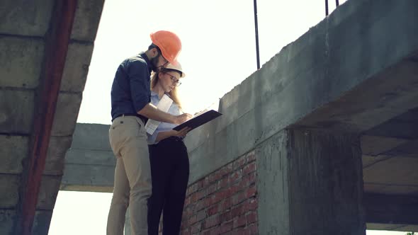 Two Architects Working On Building Model Blueprints. Engineers In Safety Helmet Construction House.