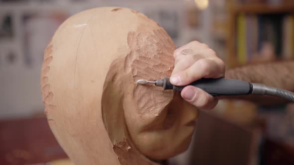 Anonymous craftsman carving wooden sculpture in workshop