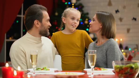 Happy Parents Kissing Adorable Daughter on Xmas Eve, Family Celebrating Holiday