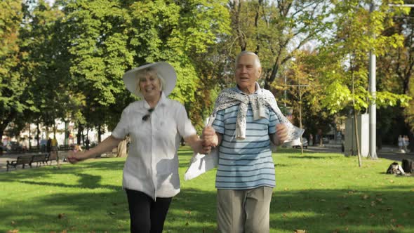 Senior Happy Two Tourists Running and Bouncing in Town Center Park