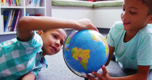 Schoolkids looking at globe in library at school