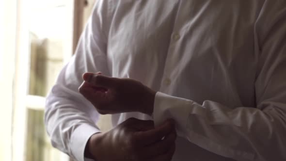 Hindu man groom fastens buttons on the shirt cuffs. Close up. Accessories Luxury wedding preparation