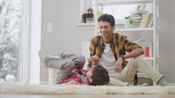 Joyful Boy Rolling to Teenage Brother and Giving Highfive