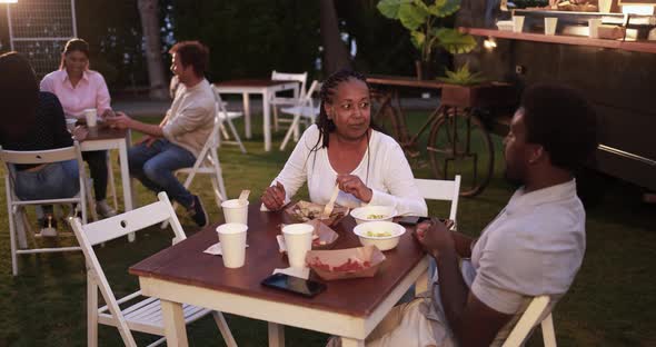 African mother and son eating food truck food outdoor - Family and summer concept