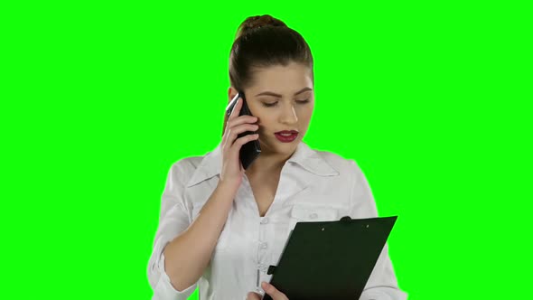 Business Woman Talking on the Phone with Folder in Hands. Green Screen