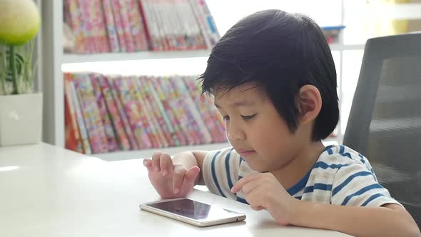 Happy Asian Child Using Mobile Phone On White Table