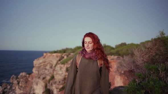 Smiling redheaded woman walking at cliff, Ibiza