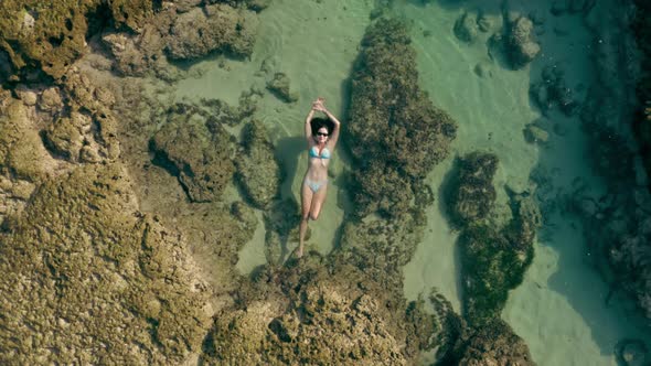 Aerial Footage of Female Person in White Bikini Laying on Natural Reef in the Ocean