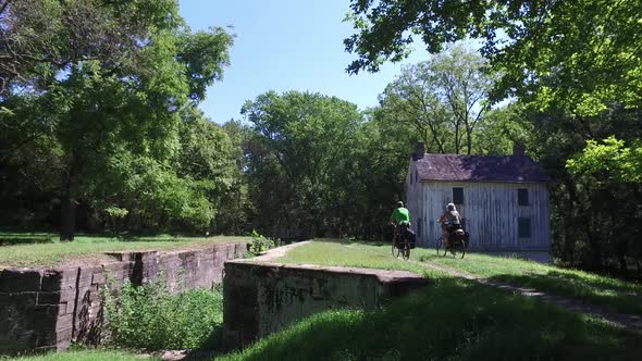 Bicycle tourists on the C&O canal in Maryland along the Potomac River going by a lock house along th