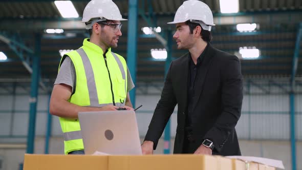 Two Factory Workers Working and Discussing Manufacturing Plan in the Factory