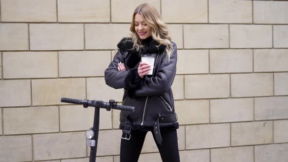 Cheerful Woman with Scooter and Takeaway Coffee