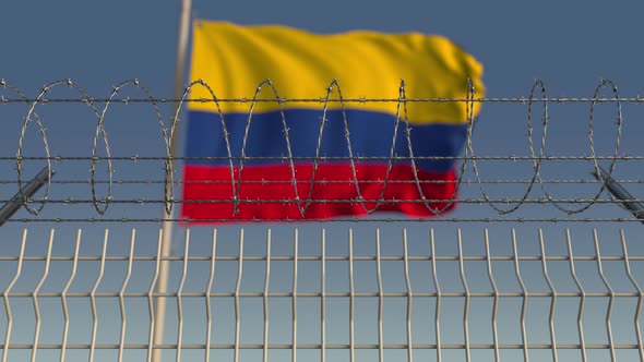 Blurred Waving Flag of Colombia Behind Barbed Wire