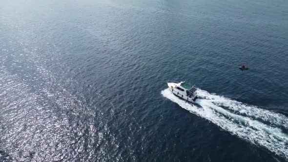 White big boat motion on blue water aerial view. Flight over a white yacht in motion