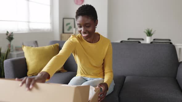 Happy Young African American Woman Unboxing Online Package at Home