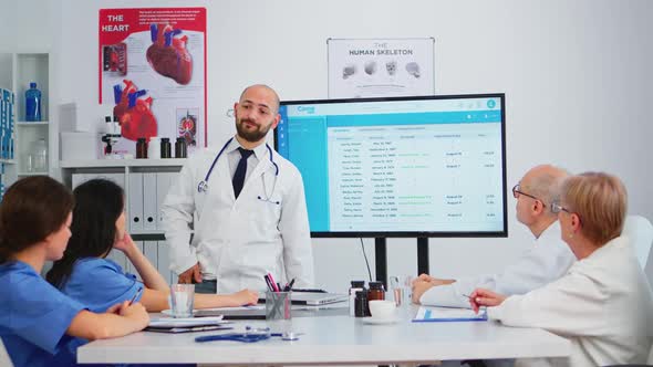 Specialist Doctor Presenting to Colleagues the Waiting List of Patients