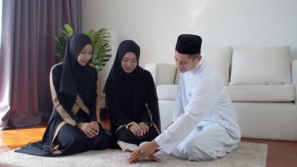 Handsome Muslim man explaining two young women read Quran 