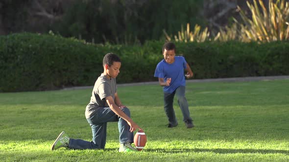 Two brothers kicking a football