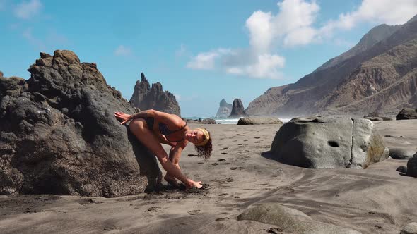 Young Woman in Bodysuit Practicing Yoga on the Beach Above Sea at Amazing Sunrise