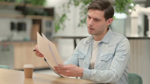 Creative Young Man Reading Documents in Office