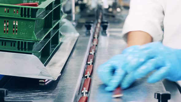 Factory Employee Is Loading Candy Bars Into the Conveyor