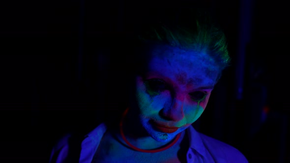 Horror Movie Concept Portrait of Woman with Flourescent Paints on Face in Darkness