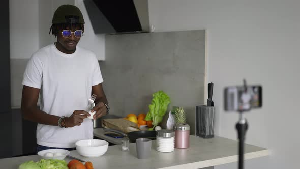 African Man Standing in Kitchen Records on Cellphone New Food Videoblog in the Morning