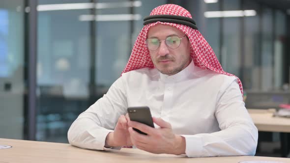 Middle Aged Arab Man using Smartphone in Office