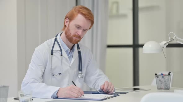 Redhead Male Doctor Writing on Paper at Work