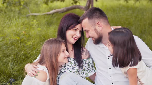 Happy Parents Spending Leisure Time with Two Cute Daughters on Fresh Air