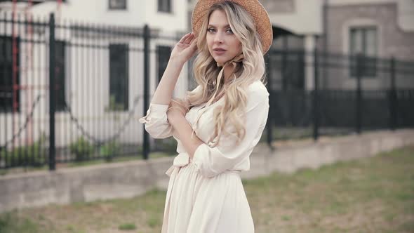 Cheerful Woman with Beautiful Big Blue Eyes Long Fair Hair White Hat in King White Dress Poses for