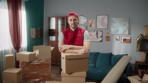 Delivery Man Holding Boxes in New Apartment and Crossing Hands