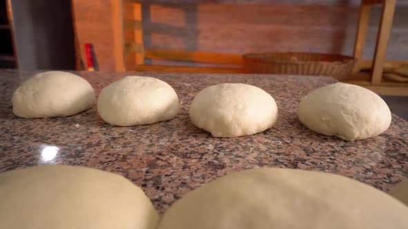 Raw yeast balls for background dough in frying pan before baking.