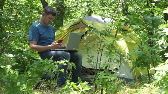 Businessman Works Behind a Laptopin Near the Tent in the Forest