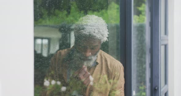 Video of sad african american senior man looking out the window