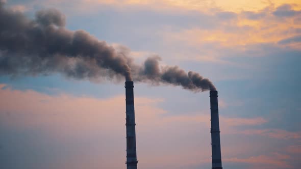 Air pollution by smoke coming out of two factory chimneys.