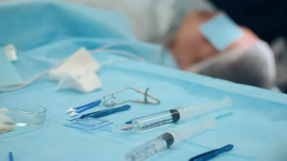 Desk with Medical Instruments and a Patient During Eye Surgery