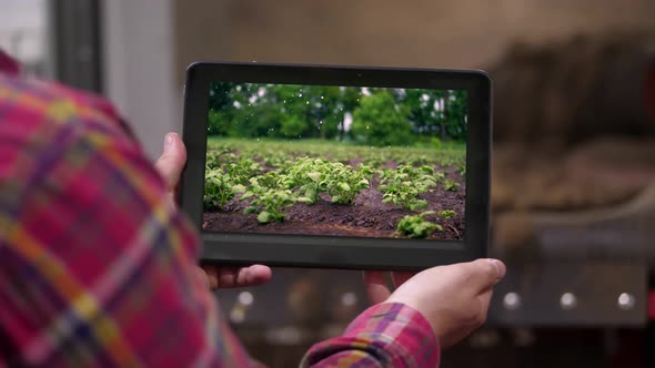 Close-up, Farmer Holds Digital Tablet in Hands on Background of Potato Storage Warehouse. It Shows
