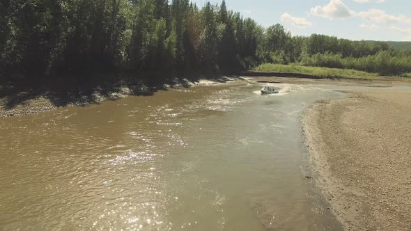 Speedboat racing towards the camera on a winding river with friends.