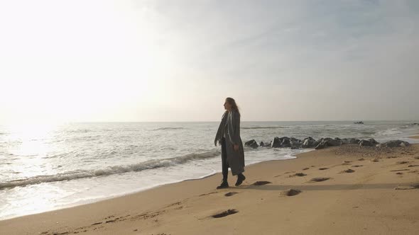 Attractive Redhead Woman in Coat Walking on the Wild Autumn Beach