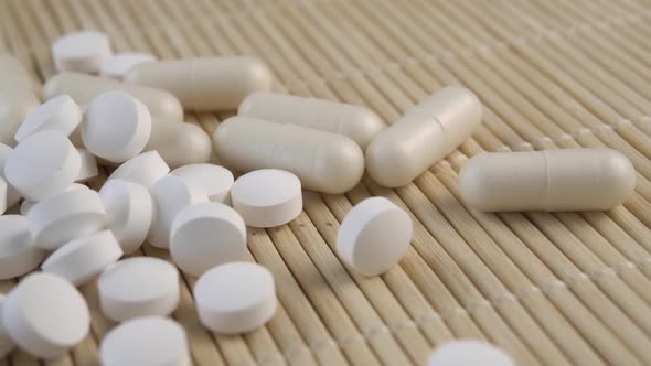 Pills and capsules close-up on a bamboo mat