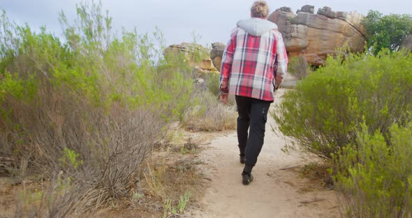 Man walking on path to rocky mountain