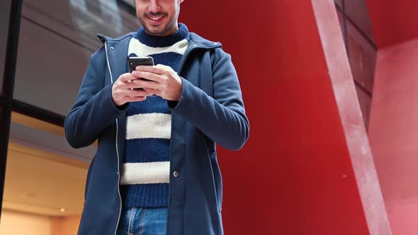 Handsome Young Man, Standing Outside the Office Building, Using Mobile Phone While Having a Break at