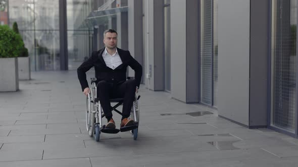 Serious Disabled Businessman in Suit Looking Ahead and Aside While Going at Street