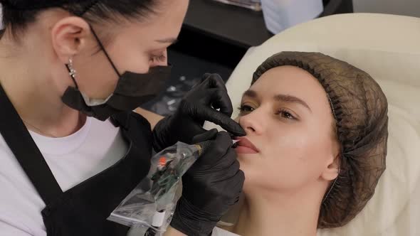 A Cosmetologist Makes Permanent Lip Makeup for a Young Woman in a Beauty Salon